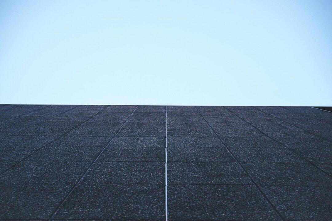 Dark textured surface against a clear blue sky.