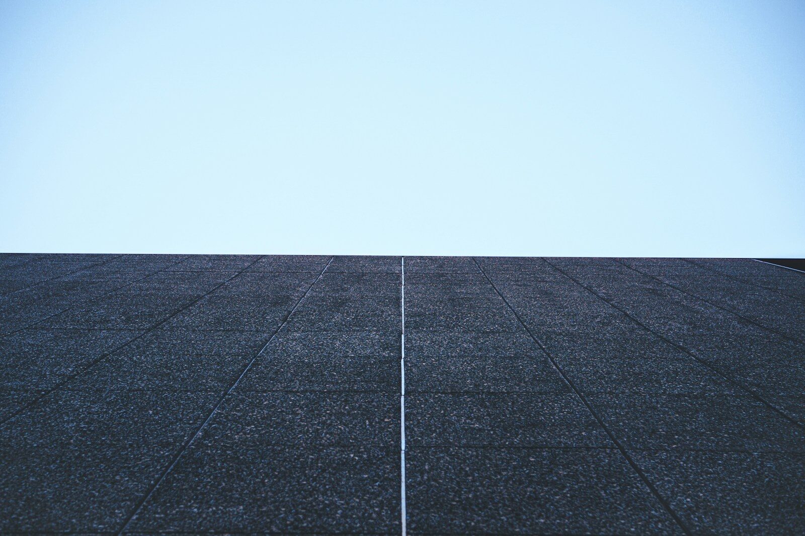 Dark textured surface against a clear blue sky.