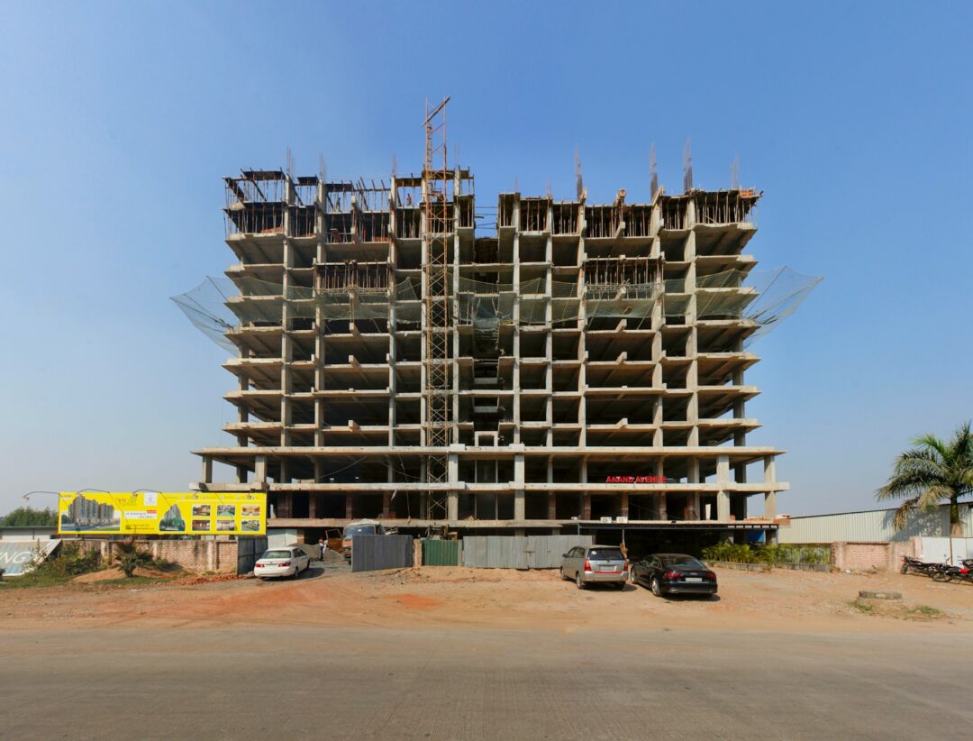 a large building under construction with cars parked in front of it