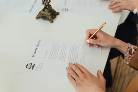 Arbitration Cannot Be Founded on Unilateral - Close-up of hands signing a divorce decree document on a desk, showcasing legal