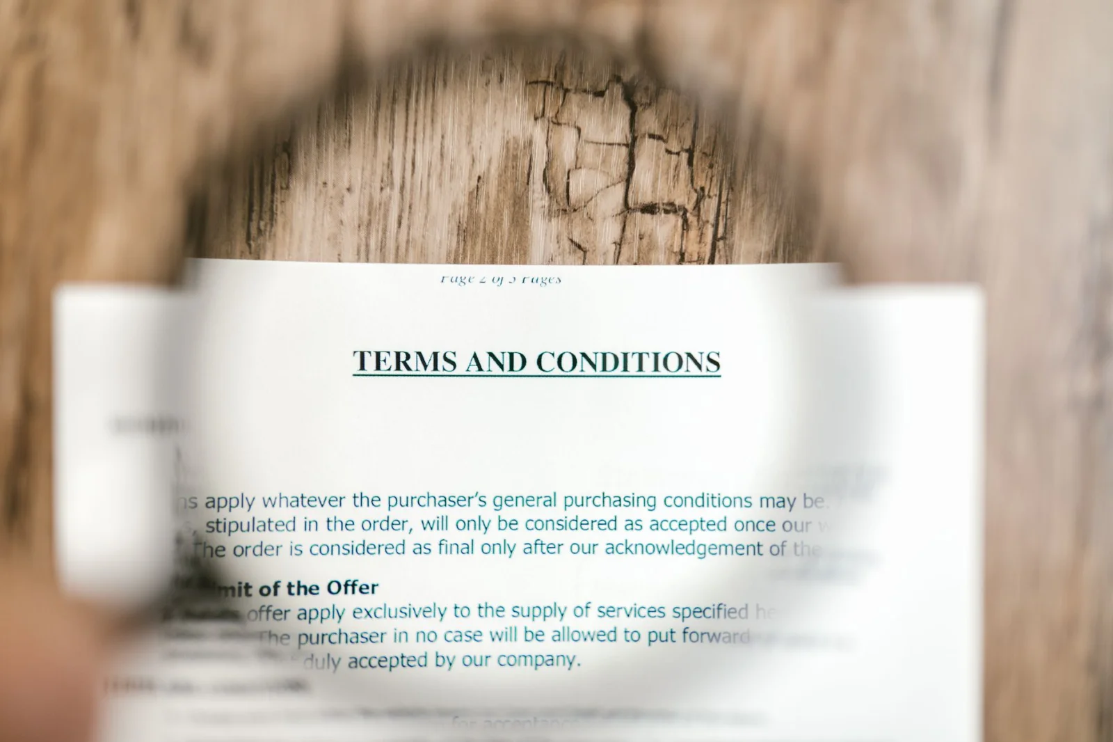 Clause in Later Agreement Incorporating All - Magnifying glass focusing on terms and conditions document on wooden surface.