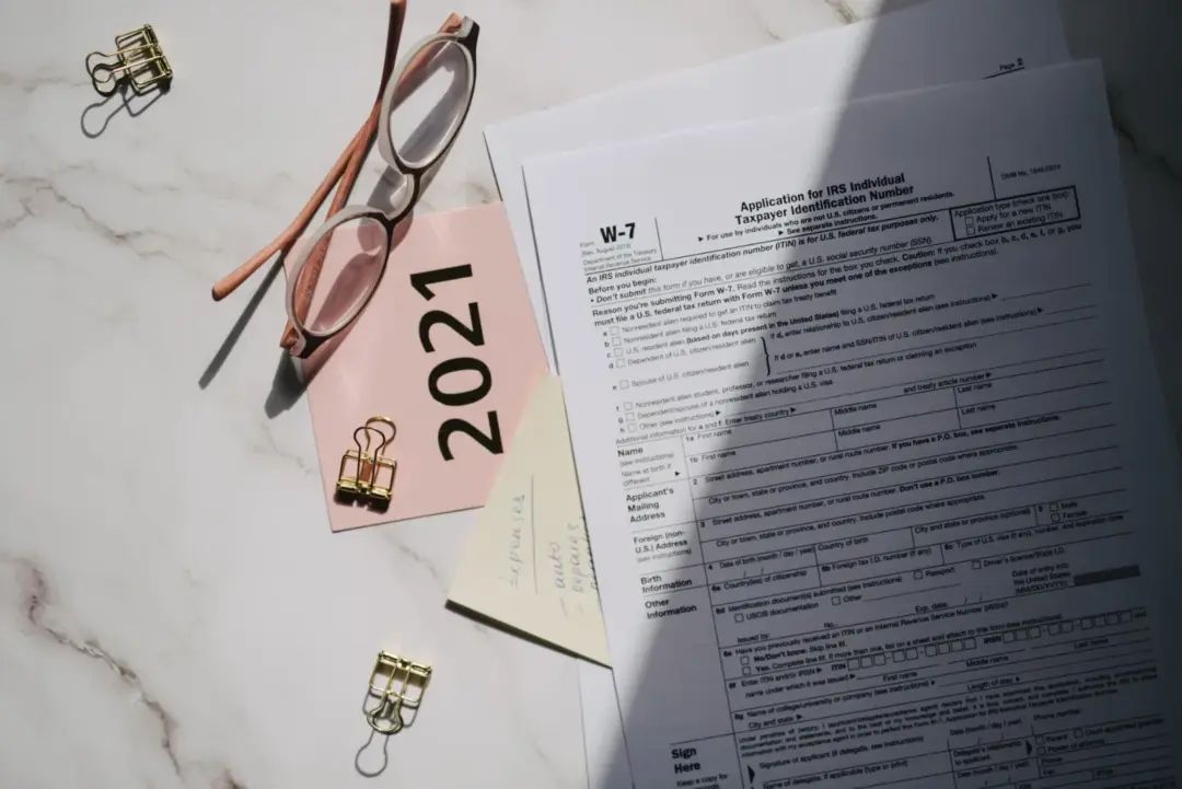Clear the Slate: A Strategic Guide - Flat lay of IRS tax documents with reading glasses and 2021 note on a marble surface.
