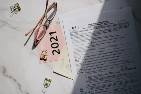 Clear the Slate: A Strategic Guide - Flat lay of IRS tax documents with reading glasses and 2021 note on a marble surface.