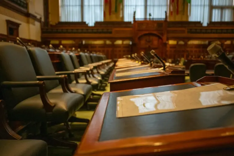 CoC Autonomy Over CIRP Costs: NCLT - A detailed view of an empty legislative chamber with rows of desks and microphones, evok