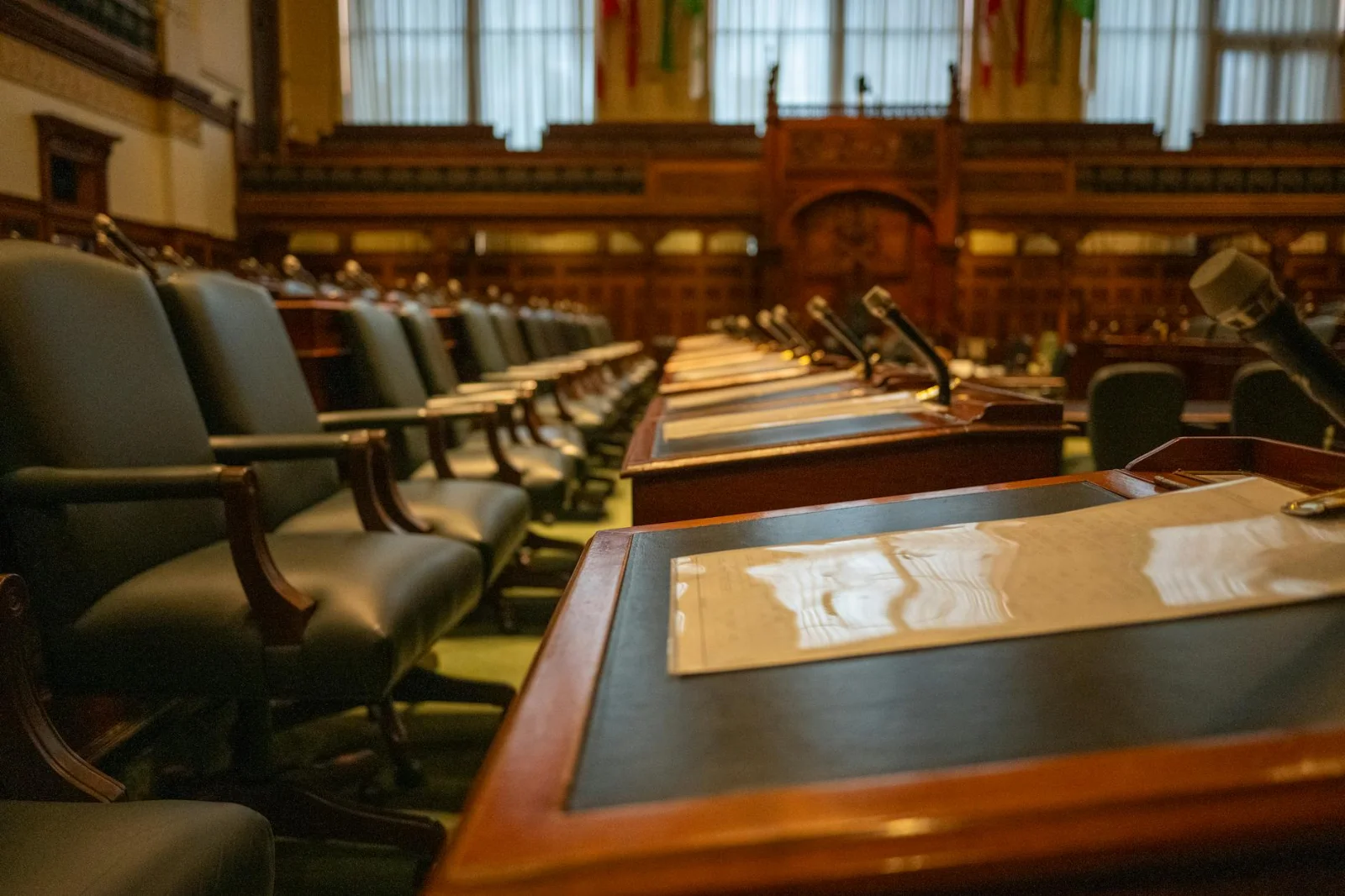 CoC Autonomy Over CIRP Costs: NCLT - A detailed view of an empty legislative chamber with rows of desks and microphones, evok
