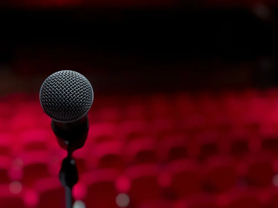Comedy, Controversy And The Constitution: Free - Close-up of microphone on stage with empty red seats in background.