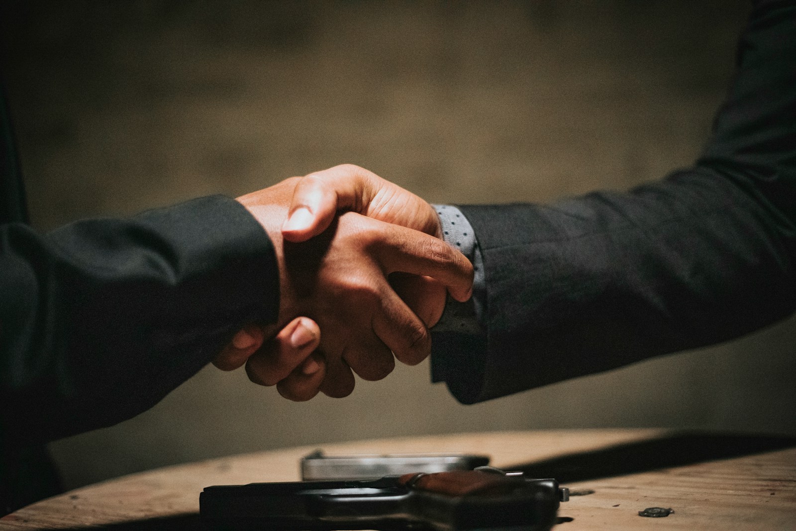 two people shaking hands over a wooden table - Agreement to Sell