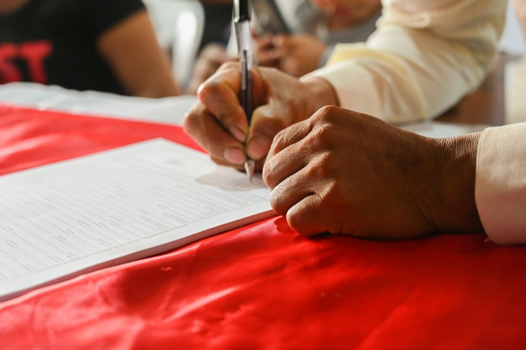 a person writing on a piece of paper - Impleading Petitions