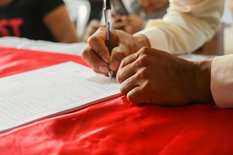 a person writing on a piece of paper - Impleading Petitions