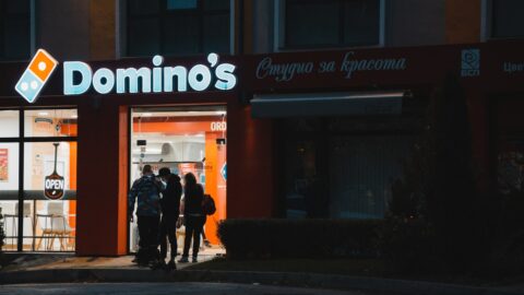 a group of people standing outside of a dominos store