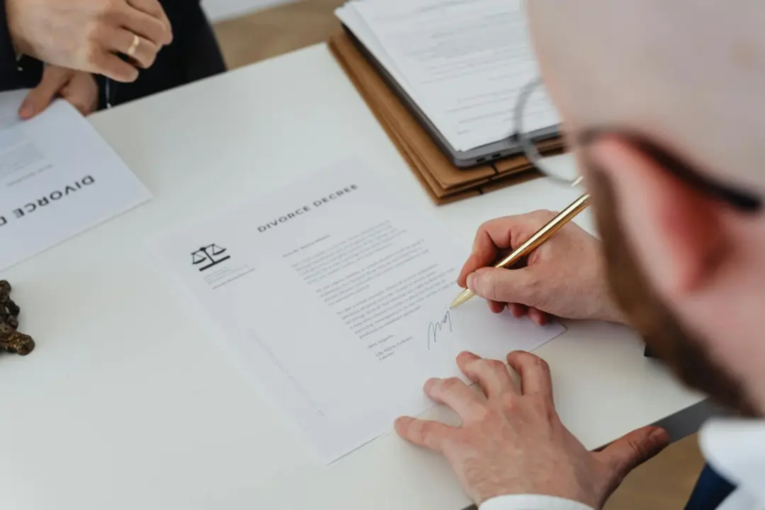 Rewriting the Rules of Resolution: The - Close-up of a person signing a divorce decree on a desk.