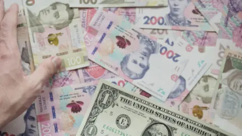 foreign currency debt conversion ibc section - Close-up of various currency notes including US dollar and Ukrainian hryvnia.