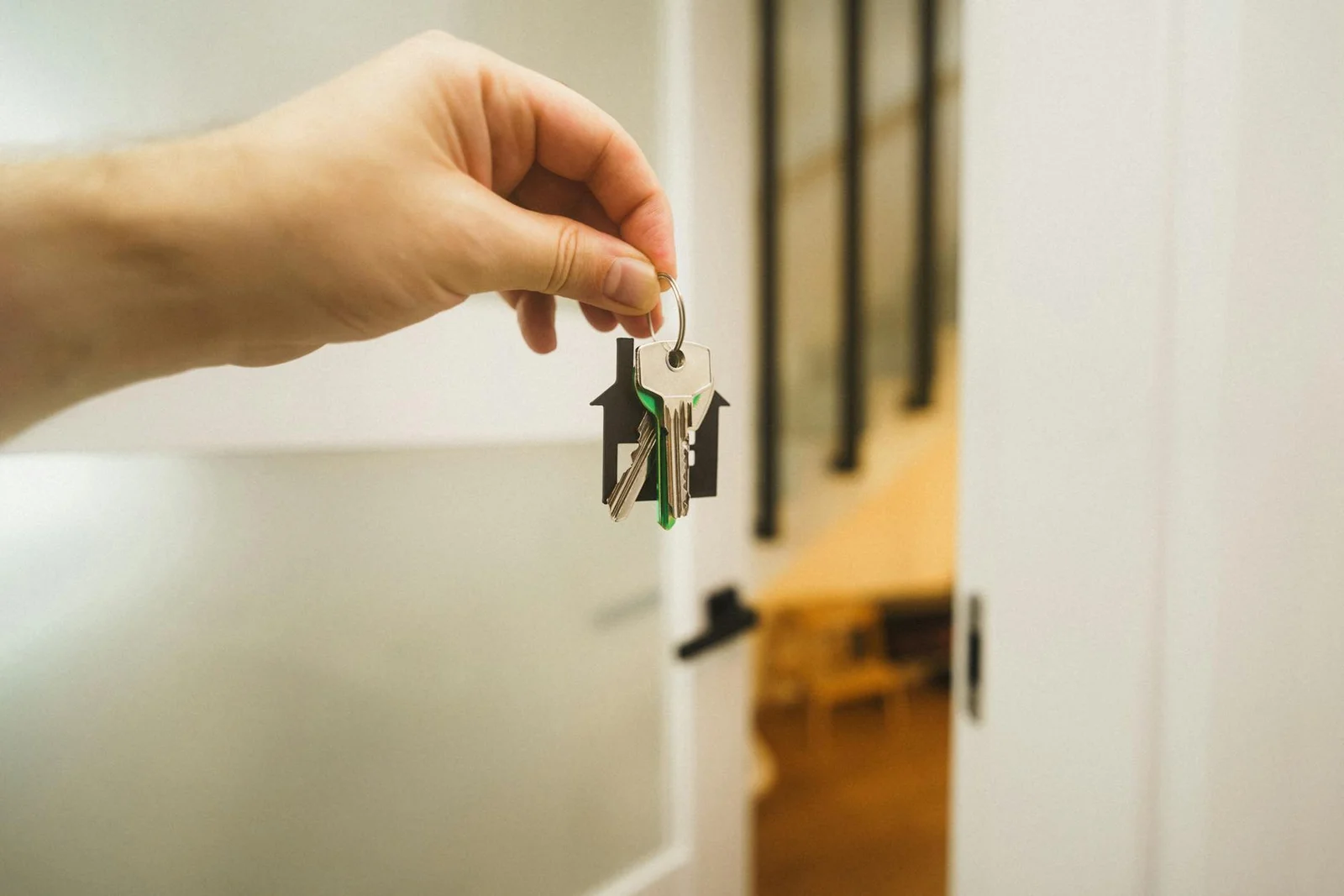 rera sale leasehold sub-lease - Sale - A hand holding a house key indoors signifies new ownership or leasing in real estate.