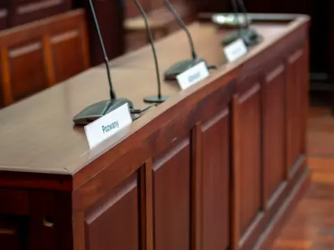 intermediary safe harbour defamation - Kerala - Empty courtroom desk with microphones and nameplates in a Polish court settin