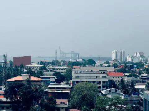 piyush kisanlal jani - The Interplay - Cityscape featuring buildings, skyscrapers, and a distant port under a clear sky.
