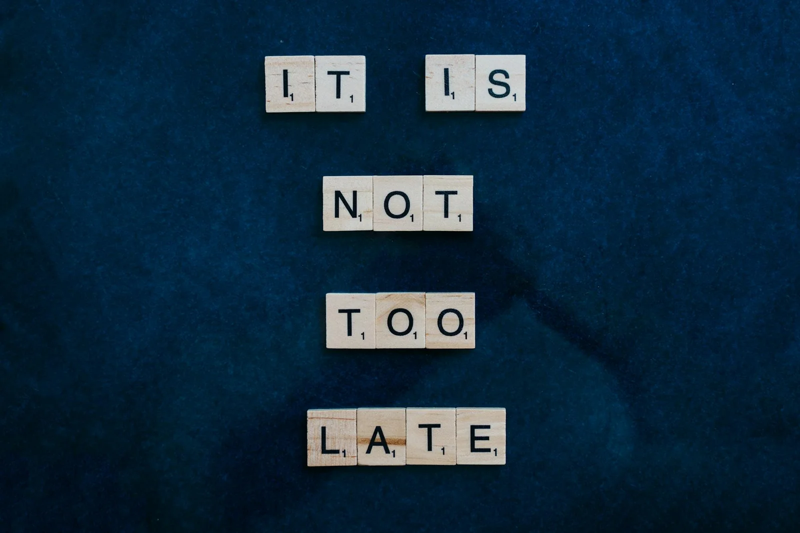 487 days - 487 Days Too - An inspiring message formed with wooden letter tiles on a dark surface: 'It is not too late'.