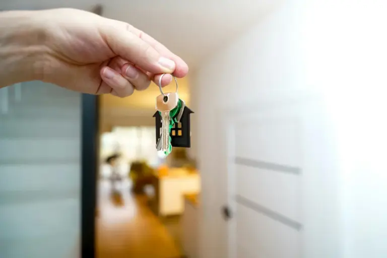 up reat rera delay interest possession - A hand holding house keys inside a modern apartment, symbolizing new property owners