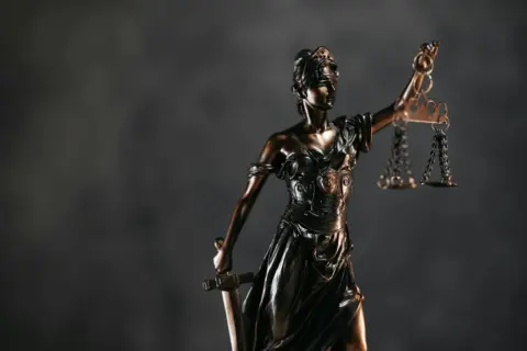 allahabad high court - Arbitration Through - Detailed bronze Lady Justice statue with scales and sword against a dark backgro