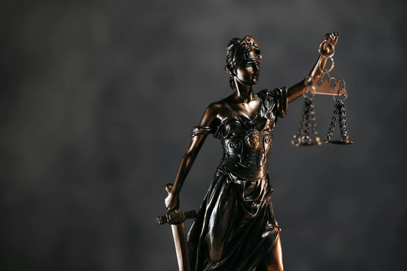 allahabad high court - Arbitration Through - Detailed bronze Lady Justice statue with scales and sword against a dark backgro