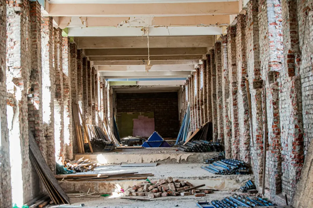 under section 14 - Restoration of - An empty industrial interior undergoing renovation, with exposed brick and construction m