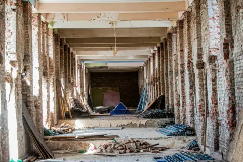 under section 14 - Restoration of - An empty industrial interior undergoing renovation, with exposed brick and construction m