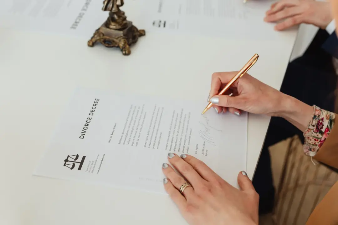 age misrepresentation fraud matrimonial consent - - Close-up of hands signing a divorce decree document on a desk, showcasing