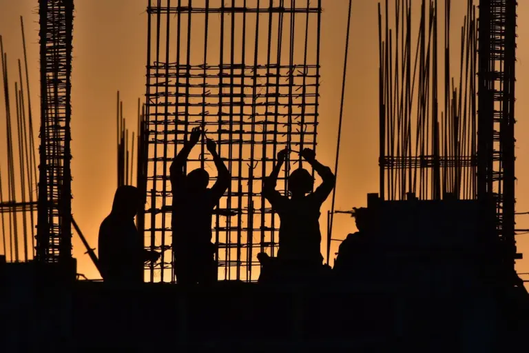 rajasthan reat krish seasons ongoing project - Silhouetted construction workers at a site during sunset, creating a dramatic