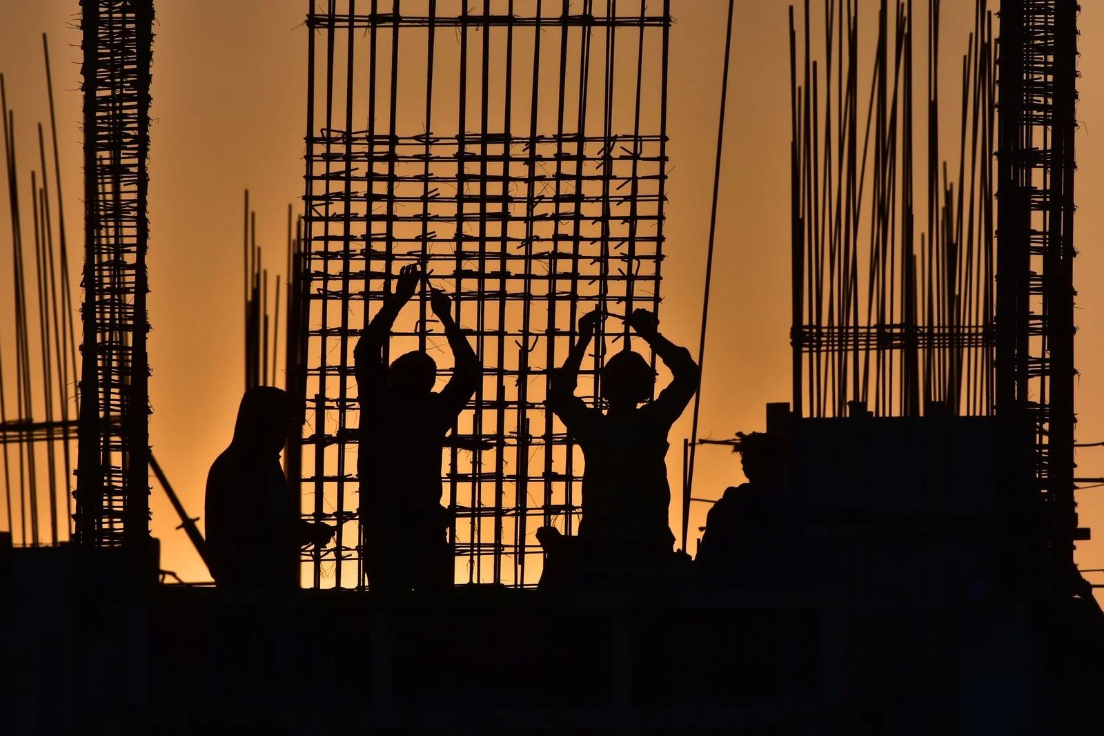 rajasthan reat krish seasons ongoing project - Silhouetted construction workers at a site during sunset, creating a dramatic