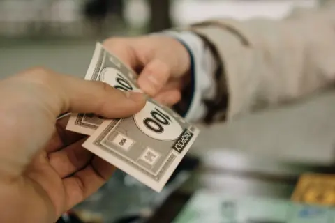 section 13(8) sarfaesi possession notice bank - Close-up of two hands exchanging Monopoly money, symbolizing a financial tran