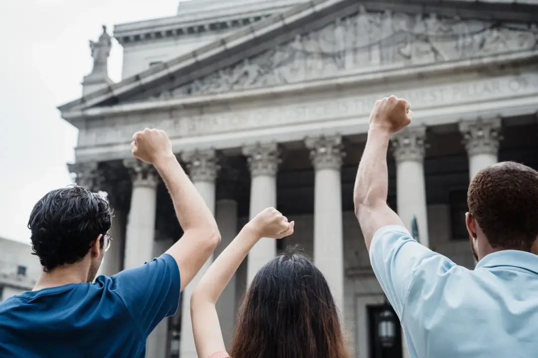 supreme court reinstatement back wages unauthorised - Three people raising fists in protest outside a government building wit