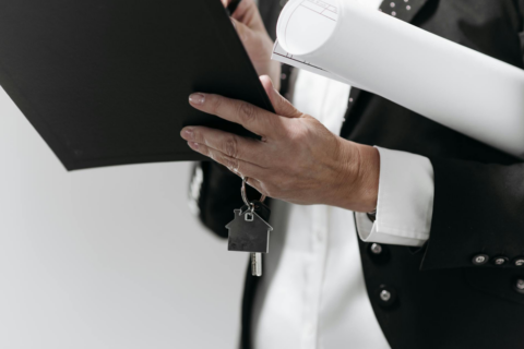 Supreme Court: Residential Sale Deed of - Close-up of a business professional holding a house key and architectural plans, sy