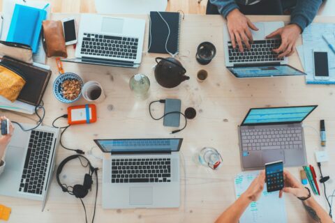 people sitting down near table with assorted laptop computers - Corporate Defamation in Digital Age