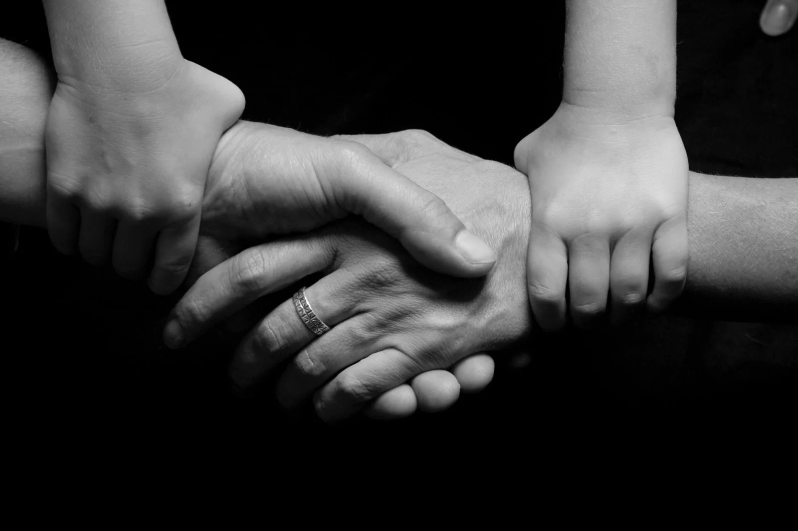 The Limitation Clock Starts with Inquiry, - Monochrome image of a child's and adult's hands clasped together symbolizing trus