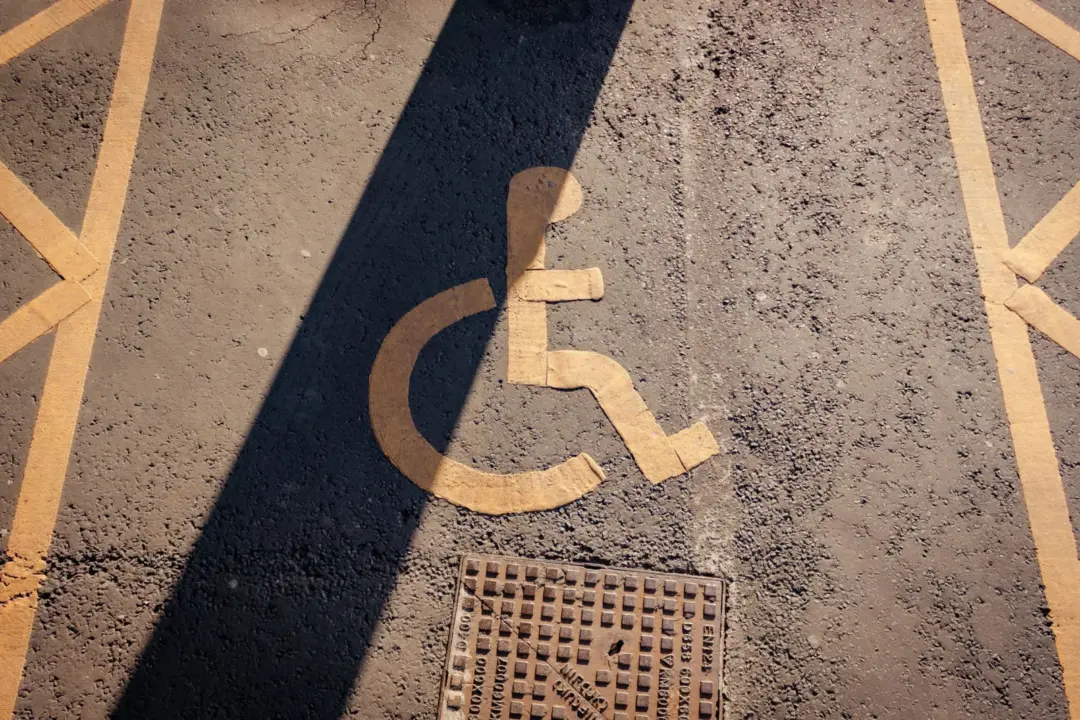 The New Accessibility Conformance Regime: Key - Close-up of a yellow wheelchair symbol painted on asphalt, highlighting acces