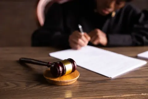 The Sole Surviving Widow’s Right to - Judge signing documents at desk with focus on gavel, representing law and justice.