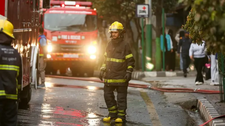 Third-Party Auditors, Digital Monitoring, and Administrative - Firefighter in uniform stands near a fire truck in the street