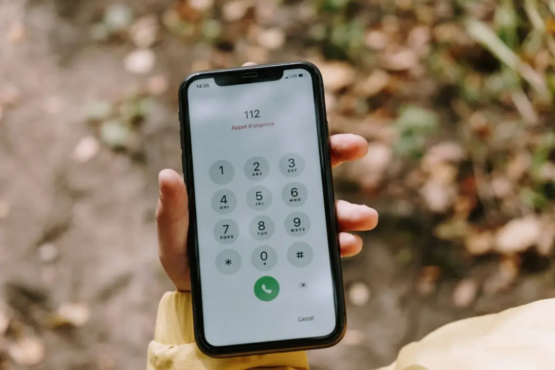 TRAI Tightens the Screws on Spam: - Close-up of emergency number dialed on smartphone held outdoors, emphasizing mobile techn