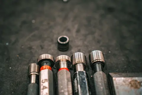 Trust-Based Governance in Legal Metrology: A - Detailed macro shot of metal industrial tools aligned on a gritty surface.