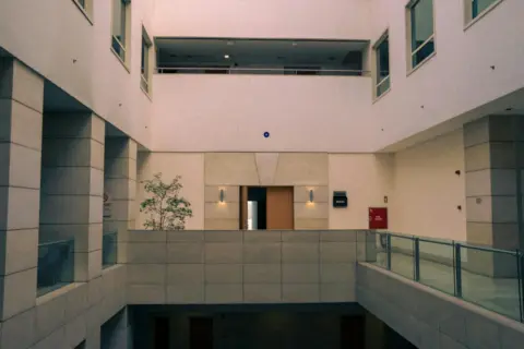 Unilateral Institutional Invocation: A Façade That - Elegant modern atrium with glass railings and minimal design in an insti