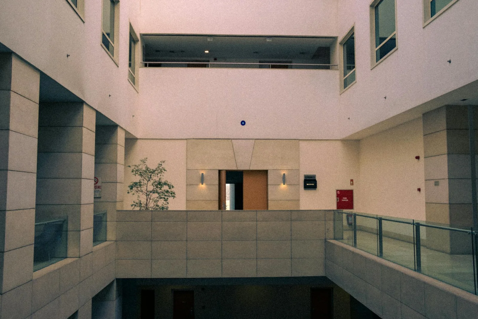 Unilateral Institutional Invocation: A Façade That - Elegant modern atrium with glass railings and minimal design in an insti